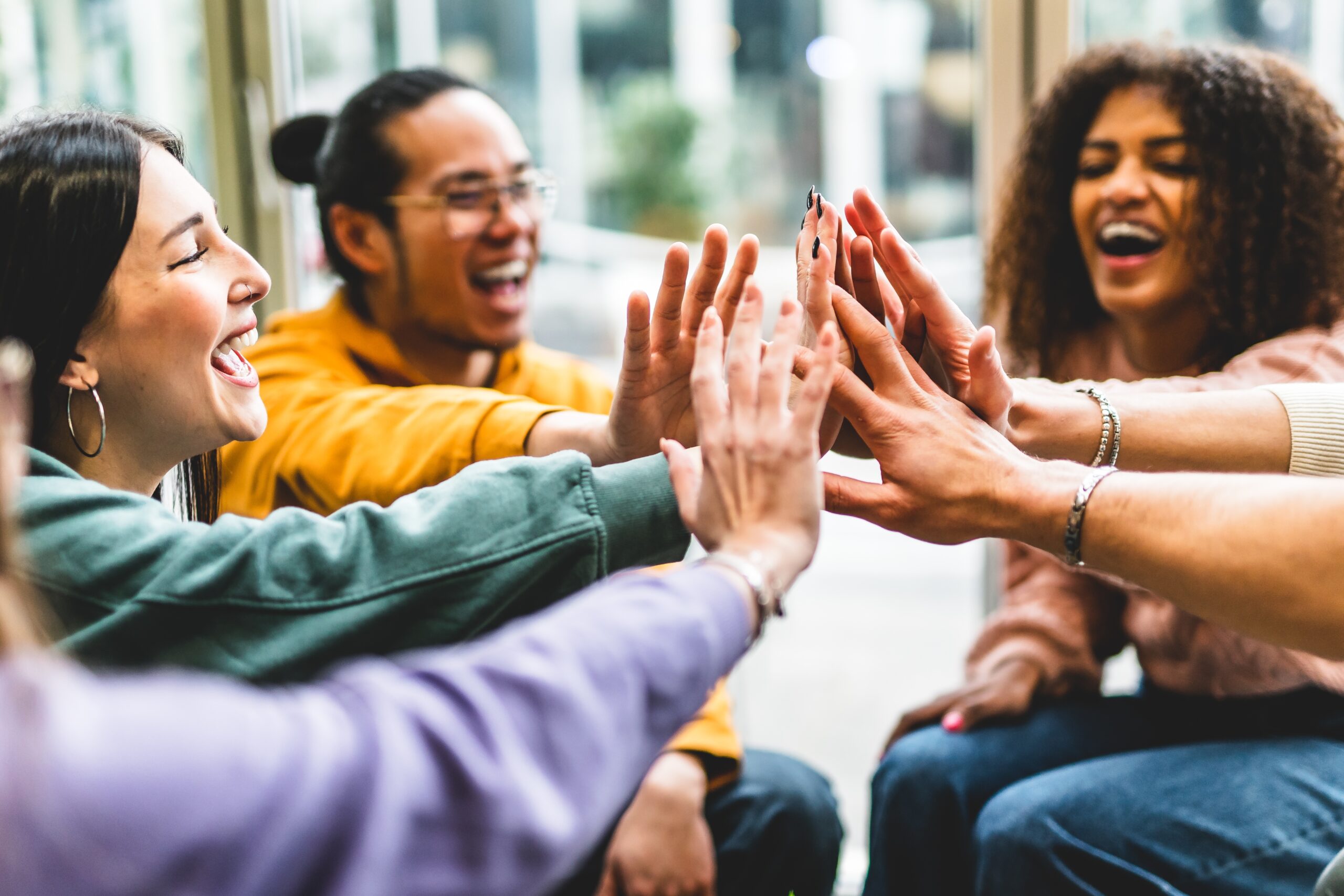 Diverse group of young professionals stacking hands in celebration, symbolizing a positive work culture