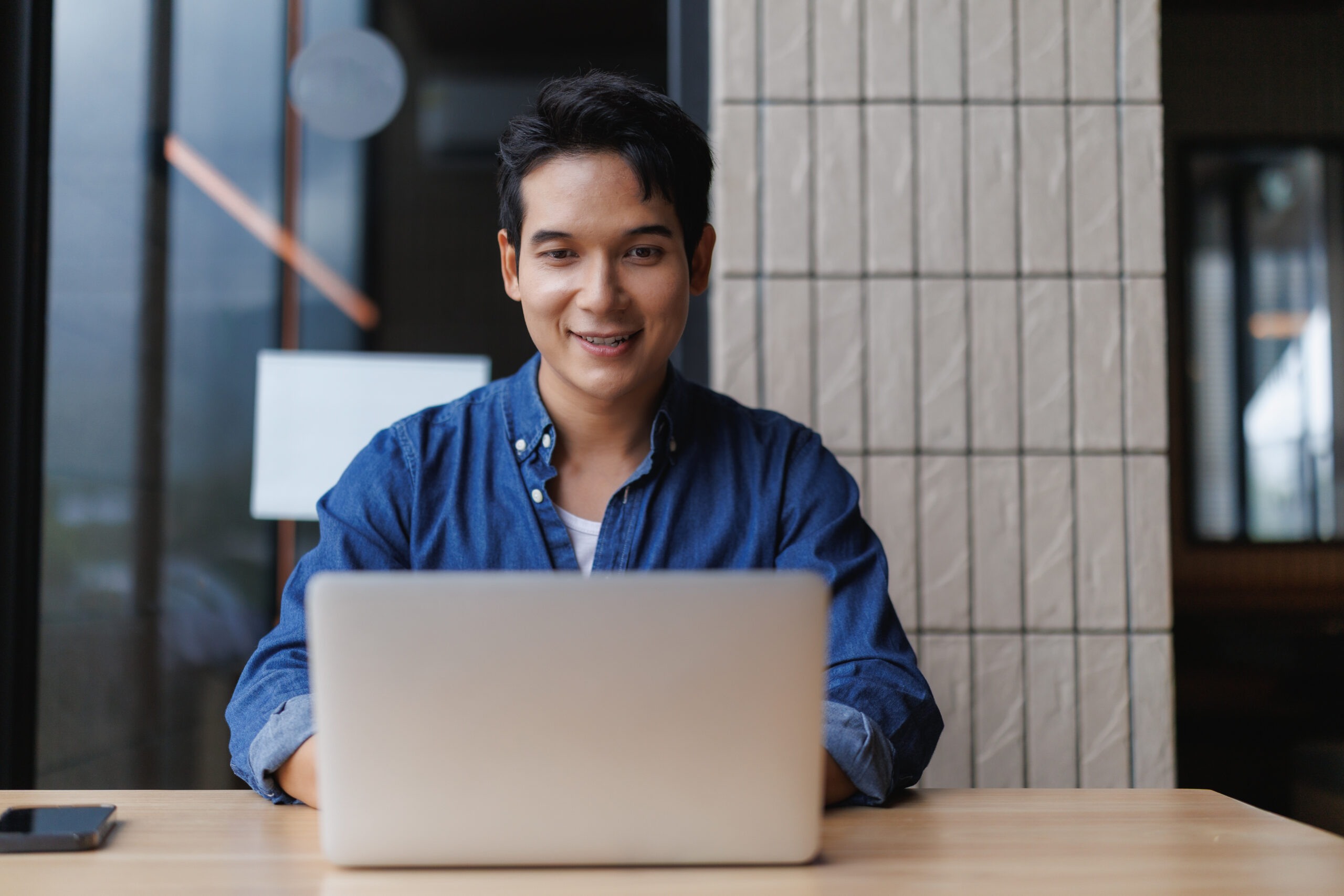 A young man doing research on his laptop in a more relaxed office environment.