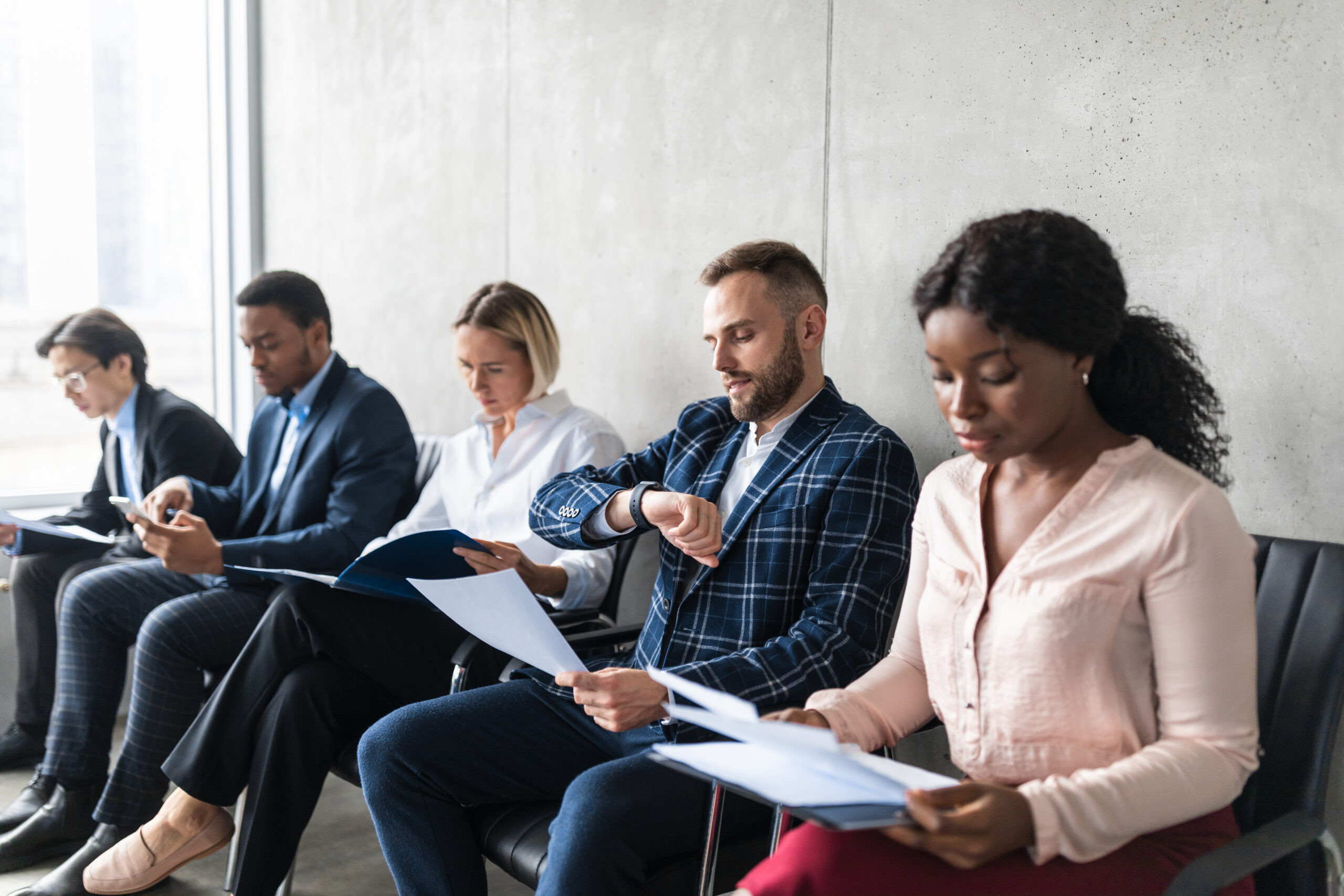 Five job applicants sitting in a row while waiting